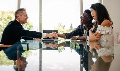 Male real estate broker shaking hands with new property owners