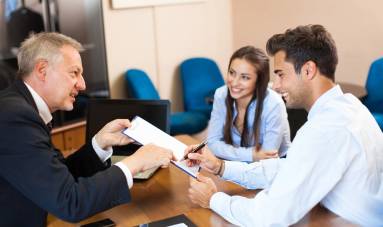 A man handing over papers to two people.