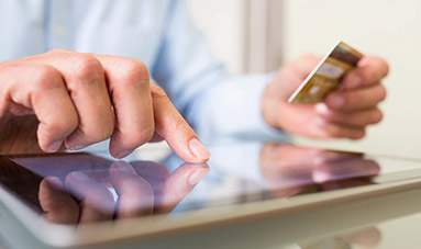 A person holding their credit card and using his cell phone.