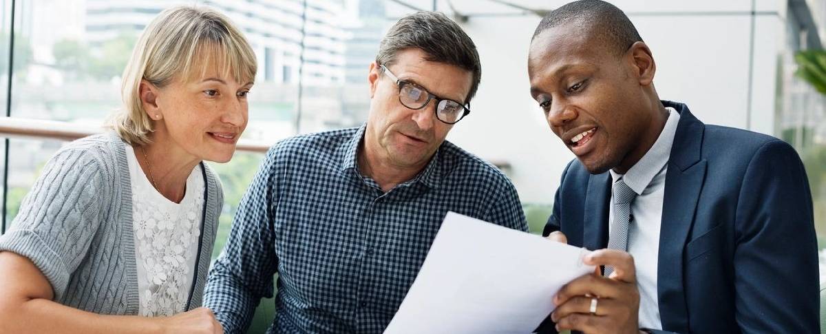 Two men looking at a paper while another man looks on.