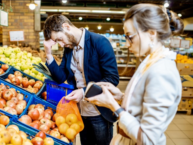 A man and woman looking at fruit in a store.