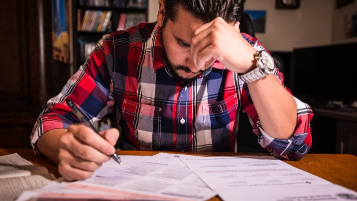 A man sitting at a table writing on paper.